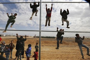 Syrian refugee children climb on a fence to watch a football training workshop in a refugee camp to provide Syrian and Jordanian trainers with football training skills, at Azraq refugee camp near Al Azraq city, Jordan